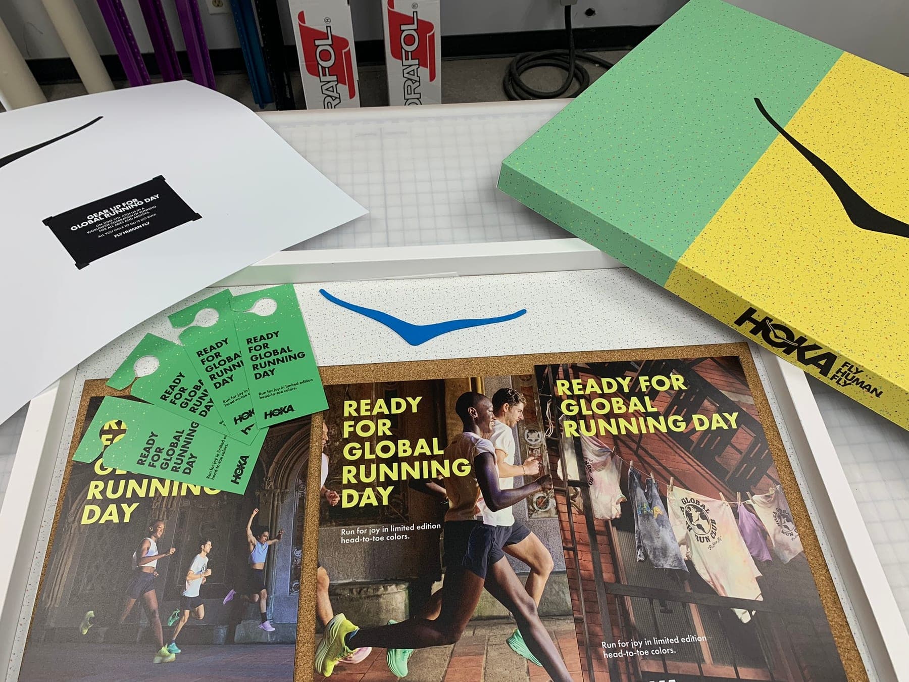 HOKA Global Running Day campaign laid out — pastel boxes, framed posters, hangtags, and stickers.